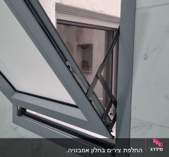 תריס פתוח עם מסגרת מתכת על קיר לבן
